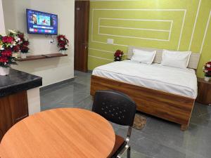 a room with a bed and a table and a tv at JMD Zoom Plaza Hotel in Farrukhnagar