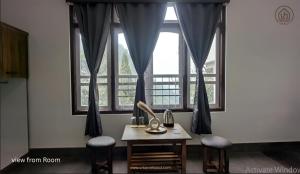 a table and two stools in front of a window at Urbane Haauz in Pelling