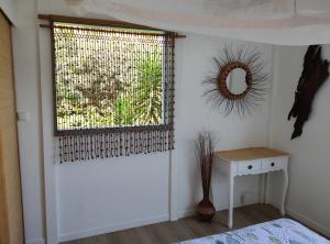 a room with a window with a table and a mirror at Chez Evelyne et Thierry in Saint-Leu