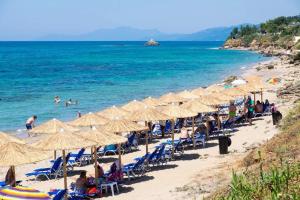 a beach with many chairs and umbrellas and the ocean at ThalaSea Studio - Apartments in Mytikas