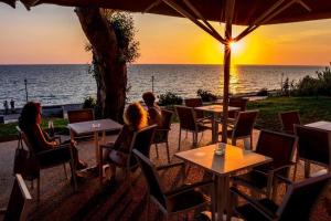 a group of people sitting at tables watching the sunset at ThalaSea Studio - Apartments in Mytikas