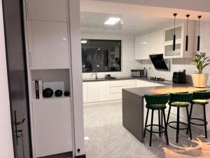 a kitchen with white cabinets and green bar stools at Blue Diamond Luxe in Gaborone