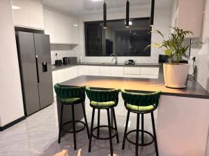 a kitchen with two green bar stools and a counter at Blue Diamond Luxe in Gaborone +1 photo