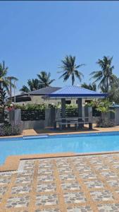 a swimming pool with a blue umbrella next to a building at Triple J Villa Puerto Galera in Puerto Galera