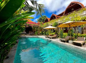 a swimming pool with chairs and umbrellas next to a house at Puri Melati in Uluwatu