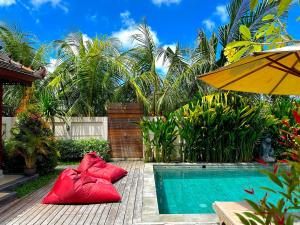 a pool with two red pillows next to a house at Puri Melati in Uluwatu