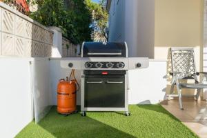 a barbecue grill on a patio with grass at August Villa Málaga. Relax Playa Piscina Coworking in Málaga
