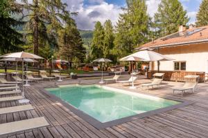 a pool with chairs and umbrellas on a wooden deck at Club del Sole Val di Fiemme Easy Camping Village in Bellamonte