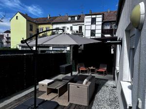 a patio with an umbrella and a table and chairs at Au Bord du Logelbach in Colmar