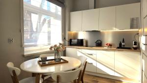 a kitchen with a small table and a kitchen with white cabinets at Studio - Apartamenty Parkowe in Gniezno