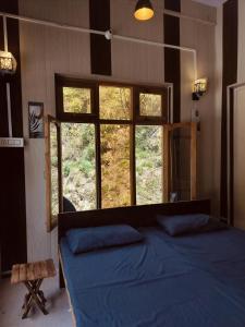 a bedroom with a blue bed and a window at Amritganga Homestay in Uttarkāshi