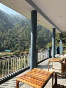a wooden bench on a balcony with a view of a mountain at Amritganga Homestay in Uttarkāshi
