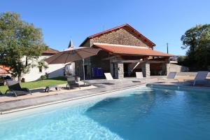 a pool with chairs and an umbrella next to a house at Elizetxea in Larceveau-Arros-Cibits