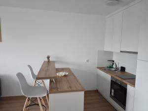 a kitchen with white cabinets and a wooden counter top at Apartman Milos in Modriča