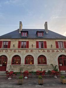 a building with red chairs and tables in front of it at HOTEL DE L'ABBAYE DE LONGPONT in Longpont