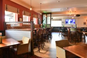 a restaurant with tables and chairs and a bar at Highwayman By Greene King Inn in Dunstable
