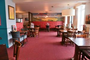 a dining room with wooden tables and chairs at Highwayman By Greene King Inn in Dunstable