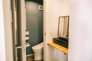 a bathroom with a toilet and a mirror at Coucou House Gra in Toyooka