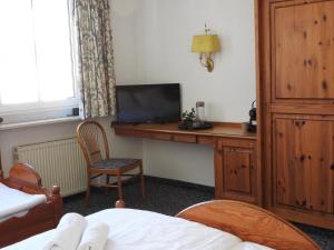 a bedroom with a desk with a television and a bed at Hotel Argo Lindau in Lindau