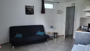 a living room with a black couch and a kitchen at studio Les merles à Saint-Égrève in Saint-Égrève