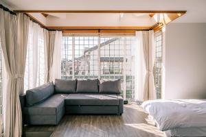 a living room with a couch and a large window at Coucou House Gra in Toyooka