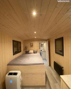 a large bed in a small room in a house at Superbe Roulotte de charme in Bagnols-en-Forêt