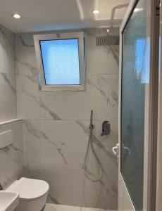 a bathroom with a shower and a toilet and a window at Xhelilaj Rooms in Vlorë