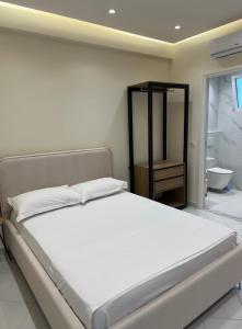 a bedroom with a large bed and a bathroom at Xhelilaj Rooms in Vlorë