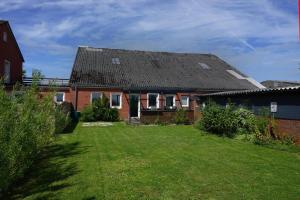 a red brick house with a grass yard at Leuchtturmnest in Krummhörn