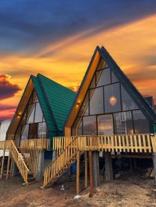 a house with a green roof and a sunset at Griya Cabin 5 Dieng in Diyeng