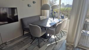 a dining room table with chairs and a television at Duinzicht, ruim appartement met terras op de begane grond nabij strand in Buren