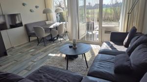 a living room with a couch and a table at Duinzicht, ruim appartement met terras op de begane grond nabij strand in Buren