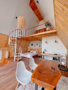 a room with a wooden table and a spiral staircase at Griya Cabin 5 Dieng in Diyeng +2 photos
