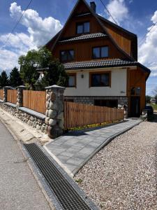 a house with a wooden fence and a sidewalk at U Stosela- wiejski dom w górach in Biały Dunajec