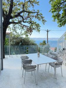 a white table and chairs on a patio at Villa Čapula - Modern Apartment with Sea View and Parking, Marušići in Omiš
