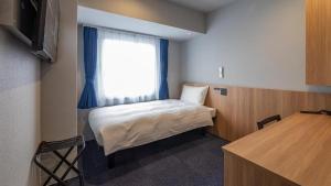 a small room with a bed and a window at Toyoko Inn Kure-eki in Kure