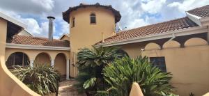 a house with a building with a clock tower at Melody Guest House in Centurion