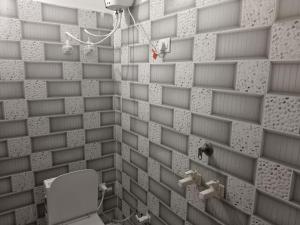 a bathroom with a white brick wall with a toilet at Sivago hotel in Kosi +4 photos