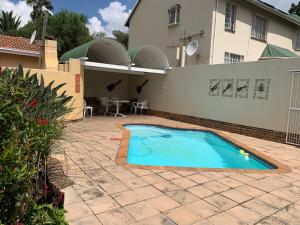a swimming pool in front of a house at Melody Guest House in Centurion