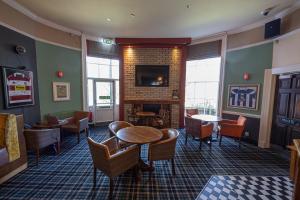 a waiting room with tables and chairs and a fireplace at The Mount by Greene King Inns in Wigan