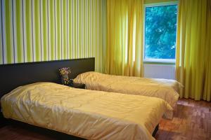 two beds in a room with yellow curtains and a window at Apartment Elegance in Stara Zagora