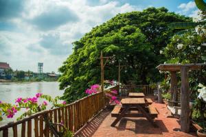 a picnic table in front of a tree by the water at Athithara Homestay in Phra Nakhon Si Ayutthaya