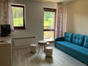 a living room with a blue couch and two stools at APT 16 Telgart in Telgárt