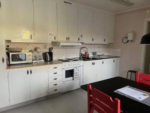 a kitchen with white cabinets and a table with a microwave at Hook&Cup in Sorsele