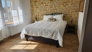 a bed in a bedroom with a brick wall at L'Atypique - Piscine chauffée - Maison en Pierre - Espaces insolites in Floing +15 photos