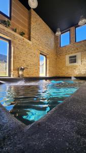 a pool of water in a room with a brick wall at L'Atypique - Piscine chauffée - Maison en Pierre - Espaces insolites in Floing