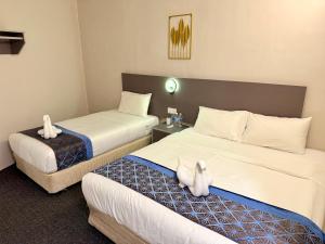 two beds in a hotel room with stuffed animals on them at Hotel first garden in Kuantan