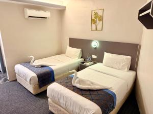 a hotel room with two beds and a couch at Hotel first garden in Kuantan