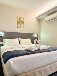 two swans sitting on a bed in a bedroom at Hotel first garden in Kuantan