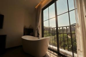 ein Badezimmer mit einer Badewanne vor einem Fenster in der Unterkunft RIN Hotel Da Lat in Xuan An + 40 Fotos